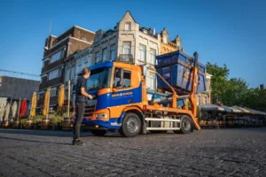 Portaalwagen die net een container optilt van de straat